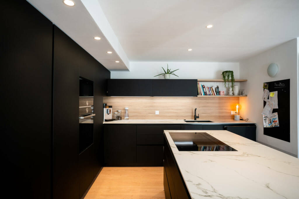 Vue générale de la cuisine noir mat, marbre et chêne clair, par l'Agence Bérénice Alandi, Architecte d'intérieur en Finistère Sud 29