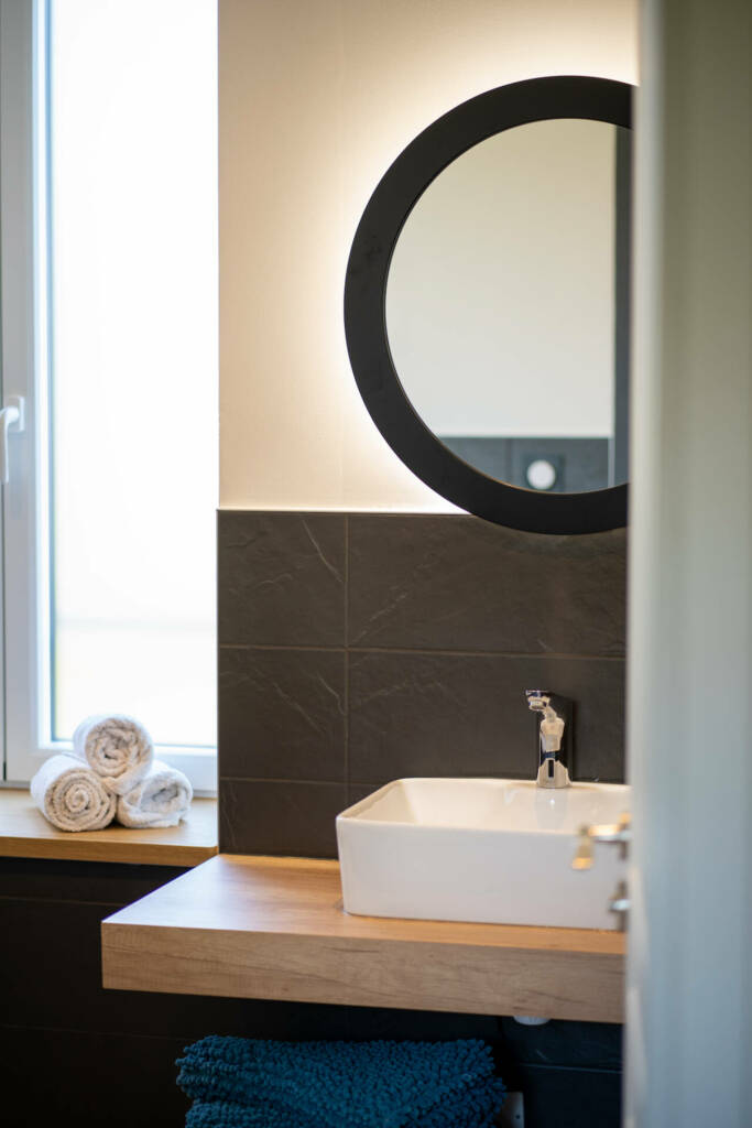 Entrée de la salle de bain et son miroir au bord noir, par l'Agence Bérénice Alandi, Architecte d'intérieur en Finistère Sud 29