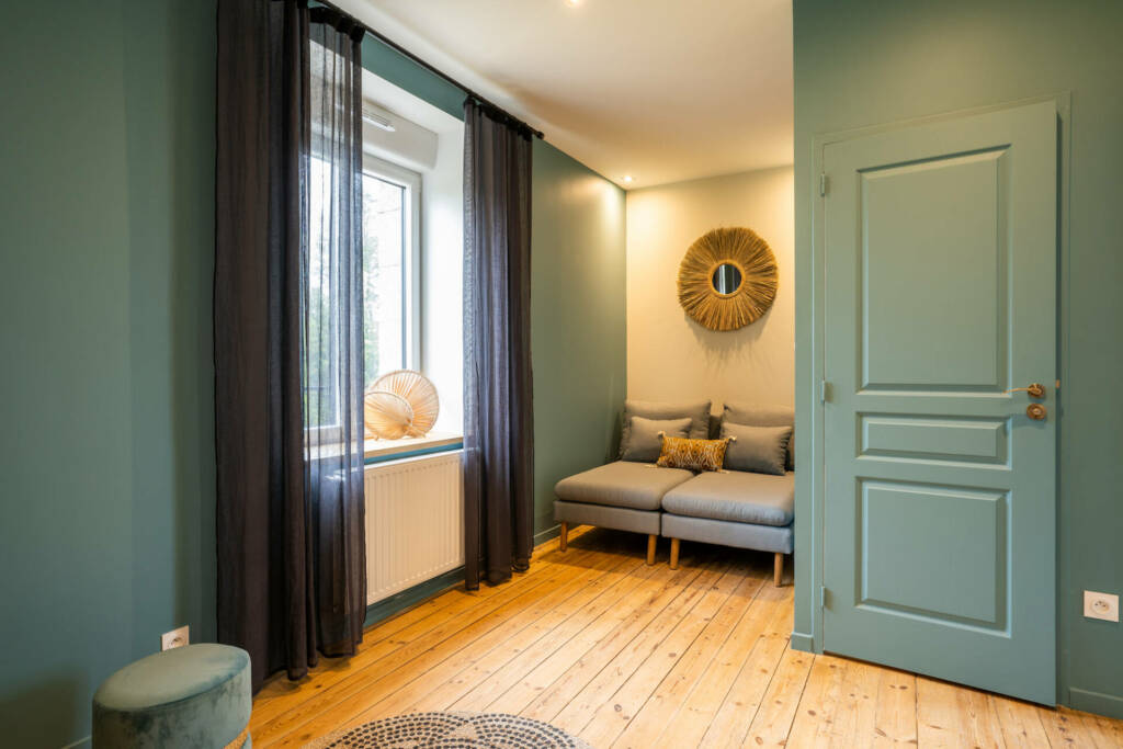 Le palier de l'étage des invités aux tonalités vert de gris avec un petit coin salon, par l'Agence Bérénice Alandi, Architecte d'intérieur en Finistère Sud 29