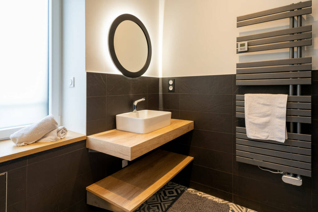 Un salle de bain aux carreaux anthracite et tablette épaisse en chêne, par l'Agence Bérénice Alandi, Architecte d'intérieur en Finistère Sud 29