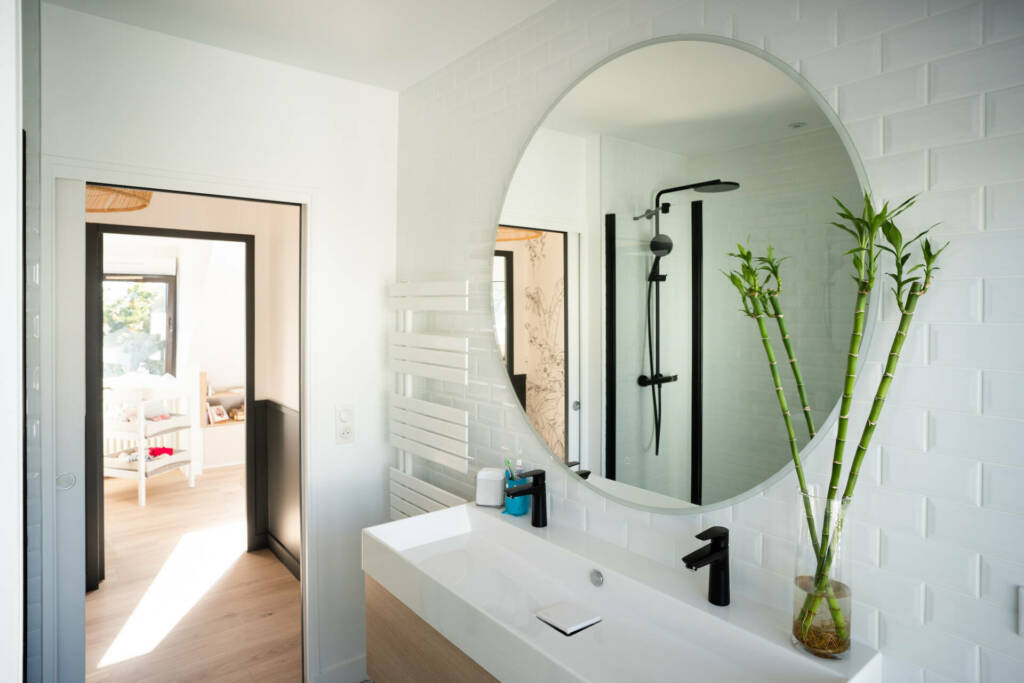 Une atmosphère très zen dans cette salle de bain au miroir rond et aux bambous décoratifs, par l'Agence Bérénice Alandi, Architecte d'intérieur en Finistère Sud 29