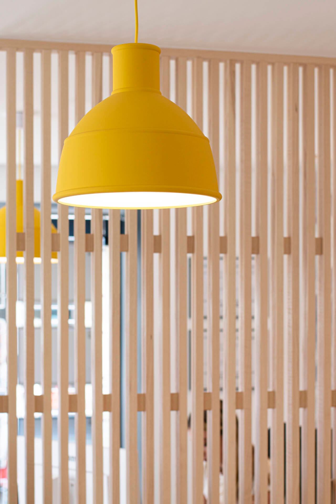 Vue du claustra et suspension jaune de l'agence immobilière, par l'Agence Bérénice Alandi, Architecte d'intérieur en Finistère Sud 29